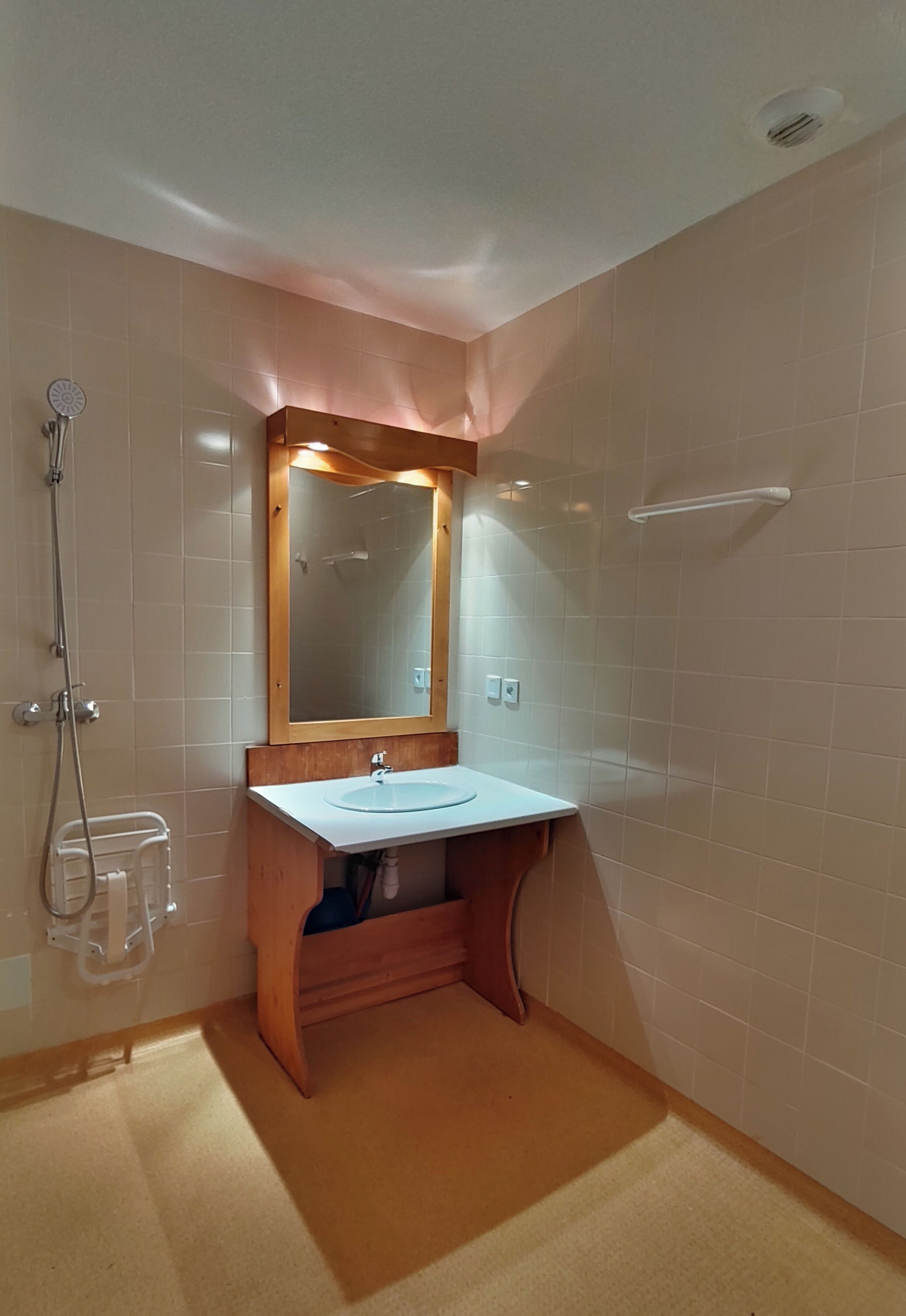 Une salle de bain avec un meuble-lavabo en bois, un miroir, un lavabo et une douche.
