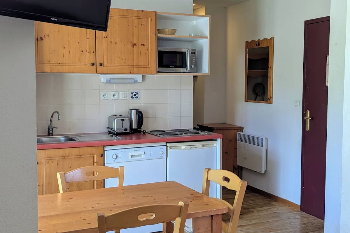 Une cuisine compacte avec des meubles en bois, un four à micro-ondes, un grille-pain et un évier.