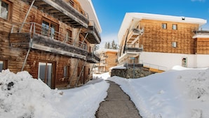 Un sendero cubierto de nieve entre edificios con fachadas y balcones de madera.