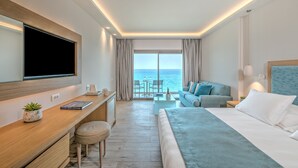 Habitación de hotel moderna con una cama grande, un escritorio, un televisor y vista al mar.