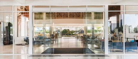 Una entrada de hotel moderna con puertas de cristal, un mostrador de recepción y un letrero que dice 'mantra on sit beach'.