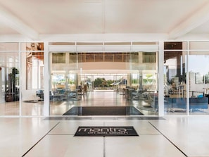 A modern hotel entrance with glass doors, a reception desk, and a sign reading 'mantra on sit beach'. - Mantra on Salt Beach (Kingscliff)