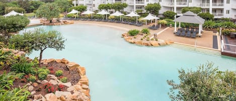 A resort with a pool, lounge chairs, and a building with balconies.