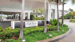 A hotel entrance with a sign reading 'Mantra on salt beach,' surrounded by palm trees and greenery. - Mantra on Salt Beach (Kingscliff)