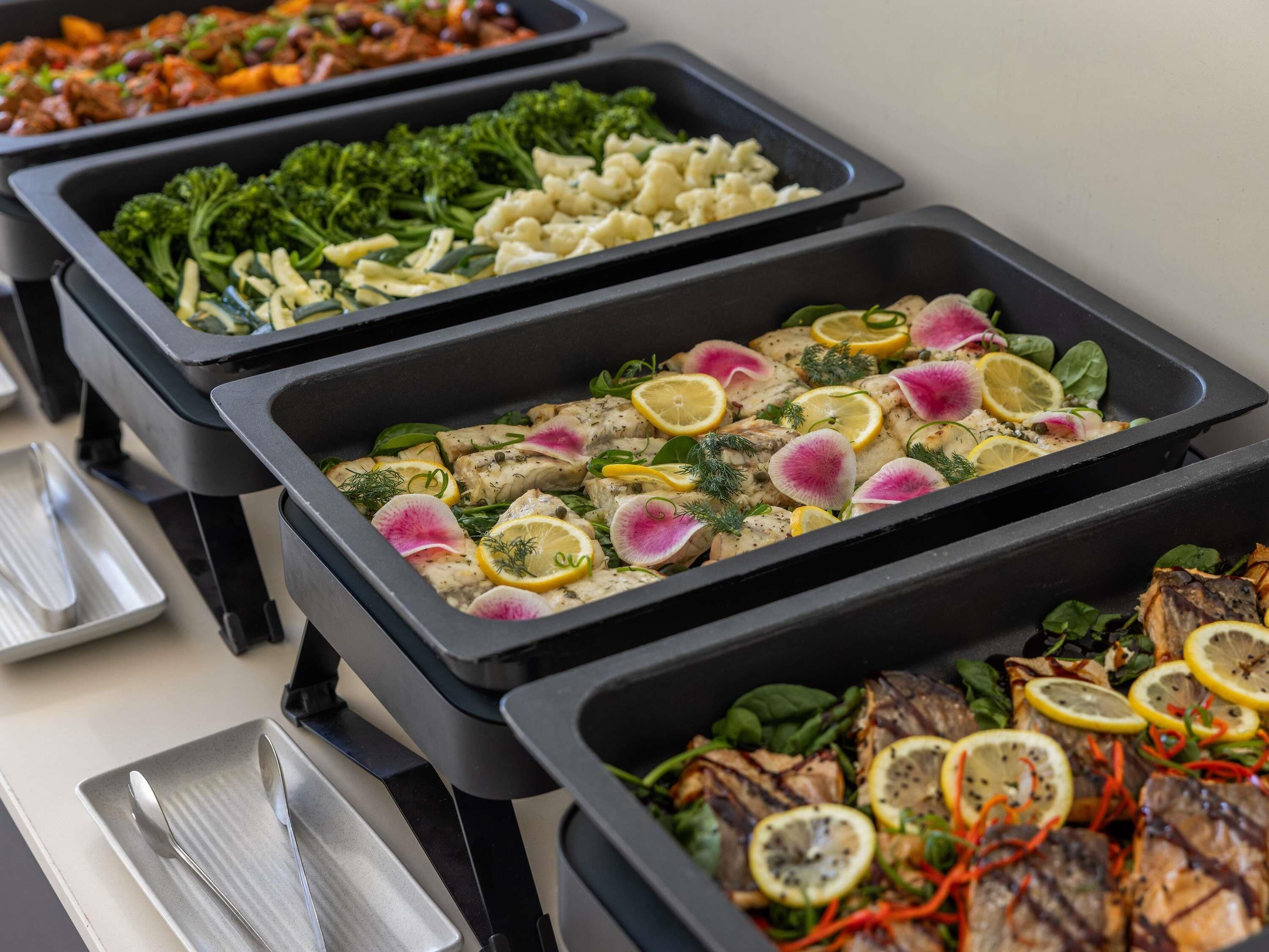 A buffet with various dishes including fish, vegetables, and salads.