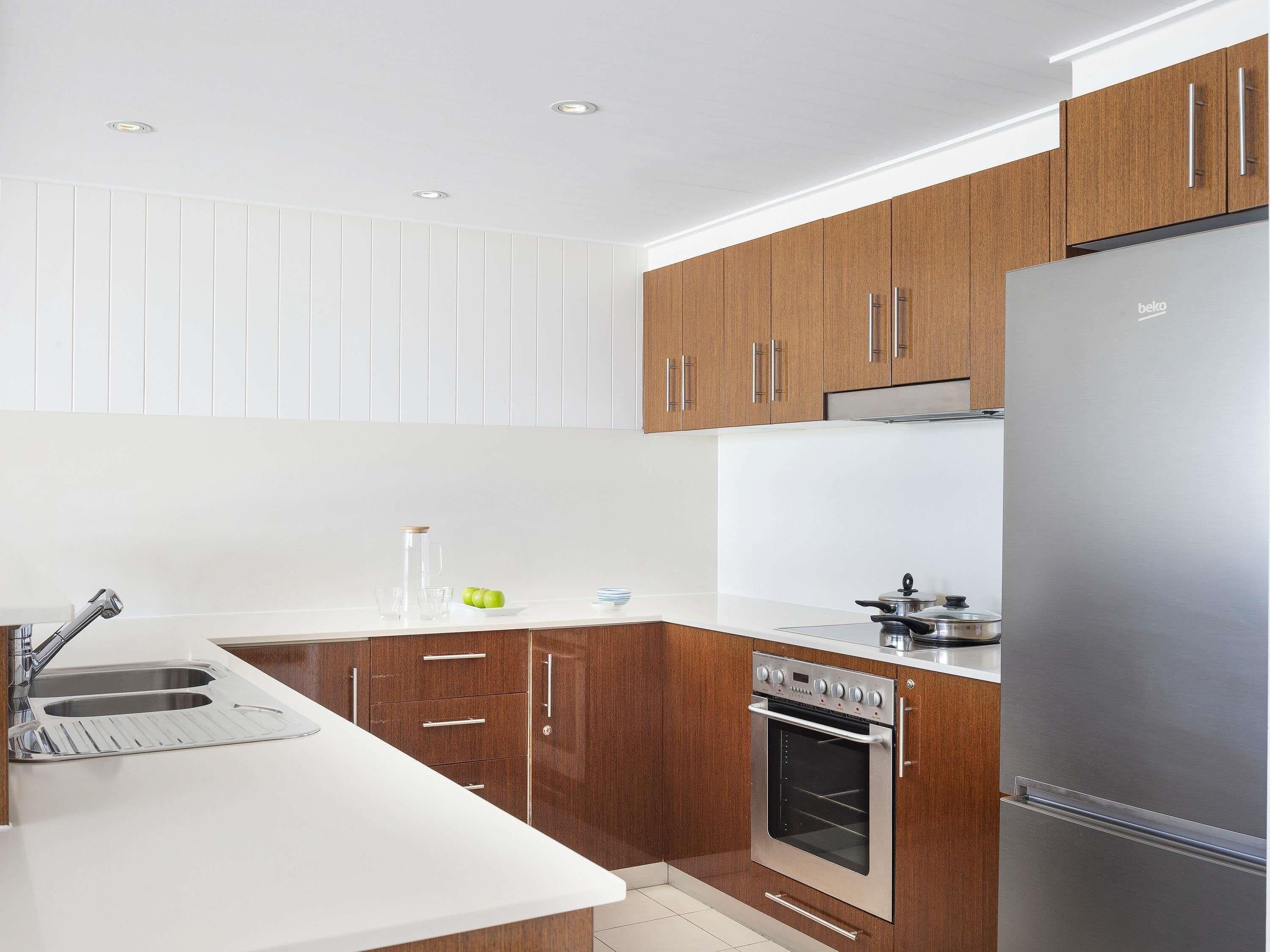 Een moderne keuken met houten kastjes, een roestvrijstalen koelkast en een inbouwoven.