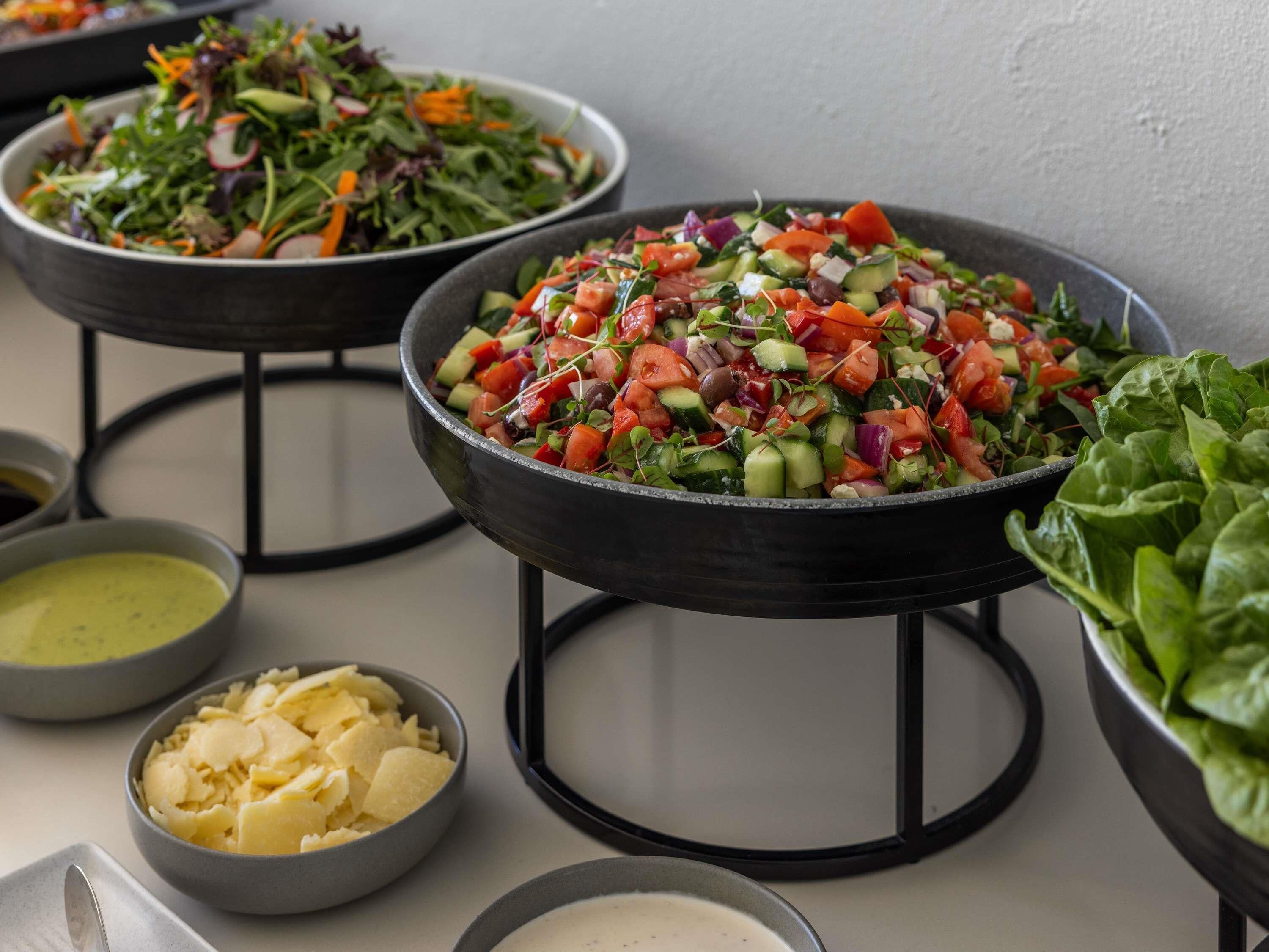 Un buffet proposant divers plats, notamment des salades, un assortiment de fromages et une variété de sauces.