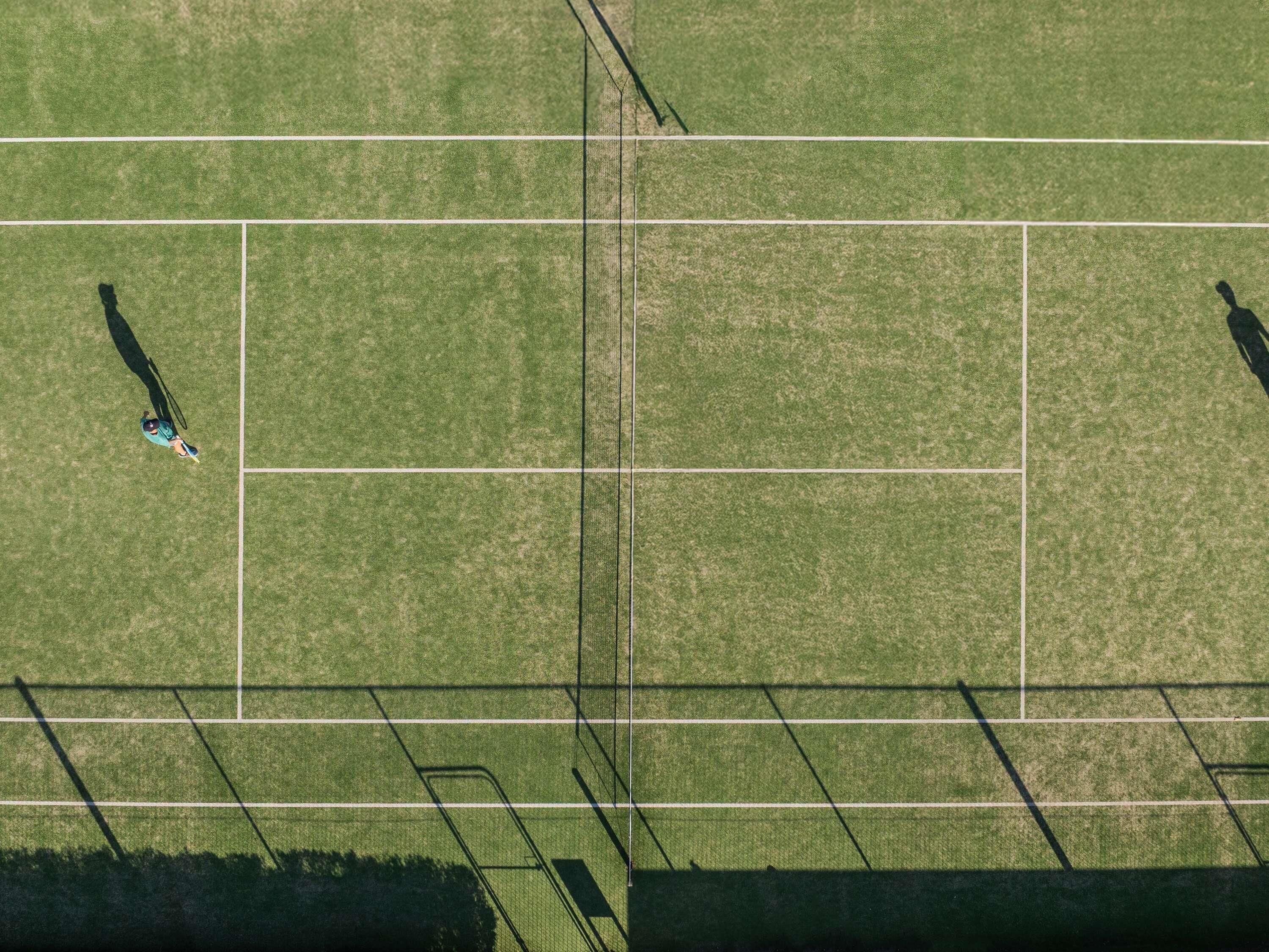 Luftaufnahme eines Sportplatzes mit markierten Bereichen und Schatten von Personen.