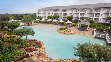 Relax by the resort's inviting pool surrounded by lush landscaping and a multi-story building with balconies.