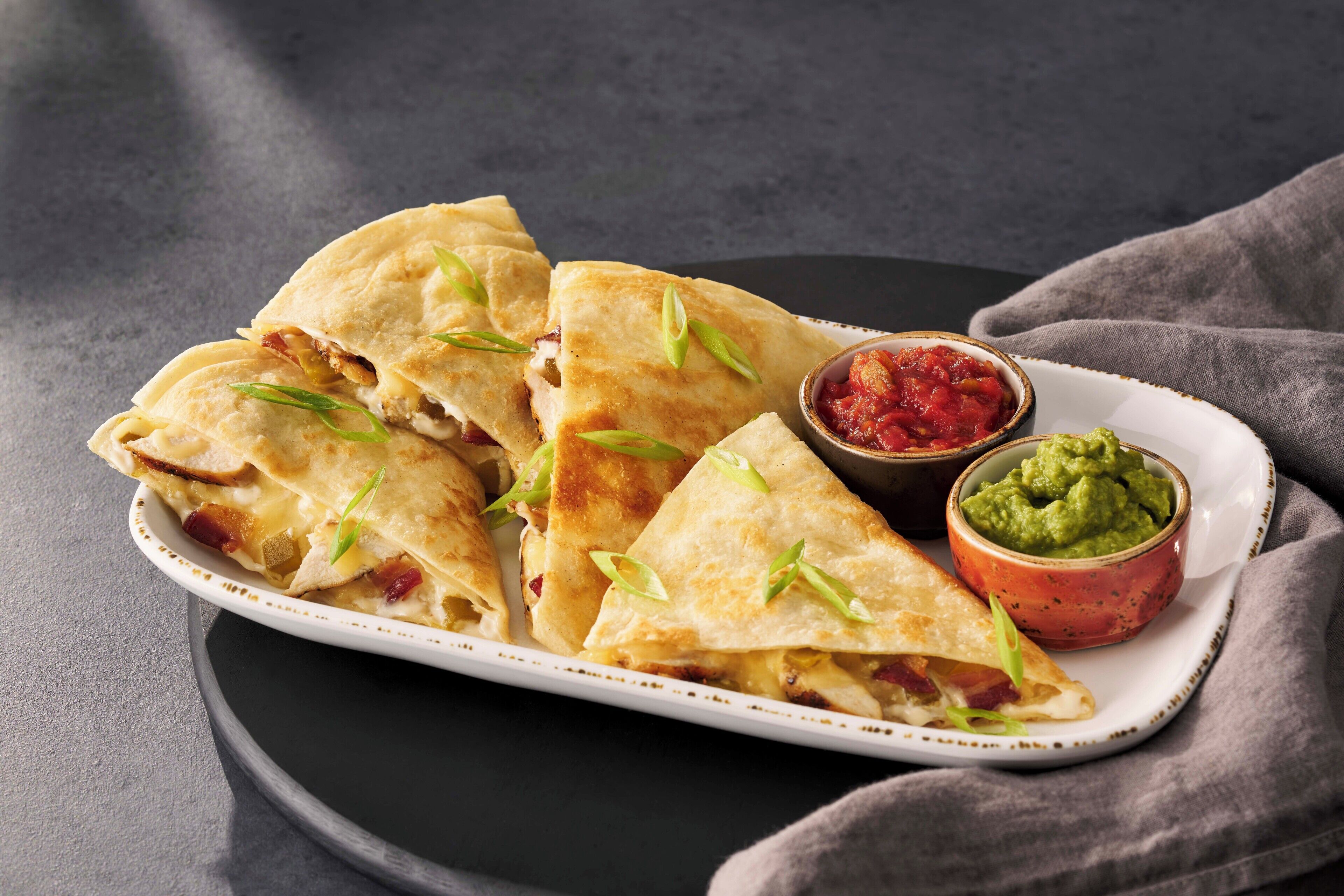 A plate of quesadillas with two dipping sauces.