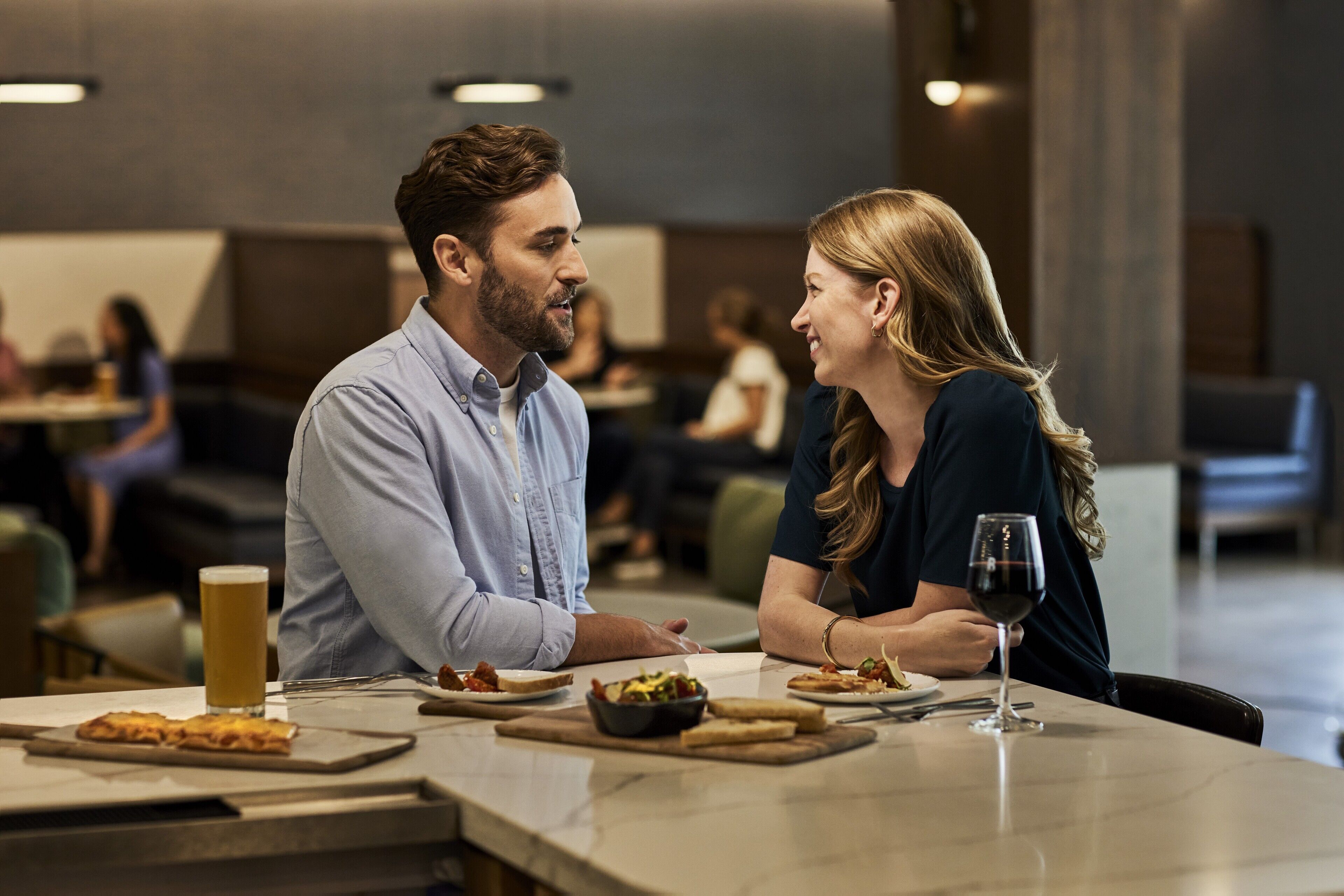 A couple dining at a restaurant with a casual setting, including a table with food and drinks.