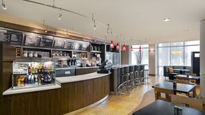 A modern cafe with a wooden counter, menu boards, and a seating area with tables and chairs. - Courtyard by Marriott Lancaster (Lancaster)