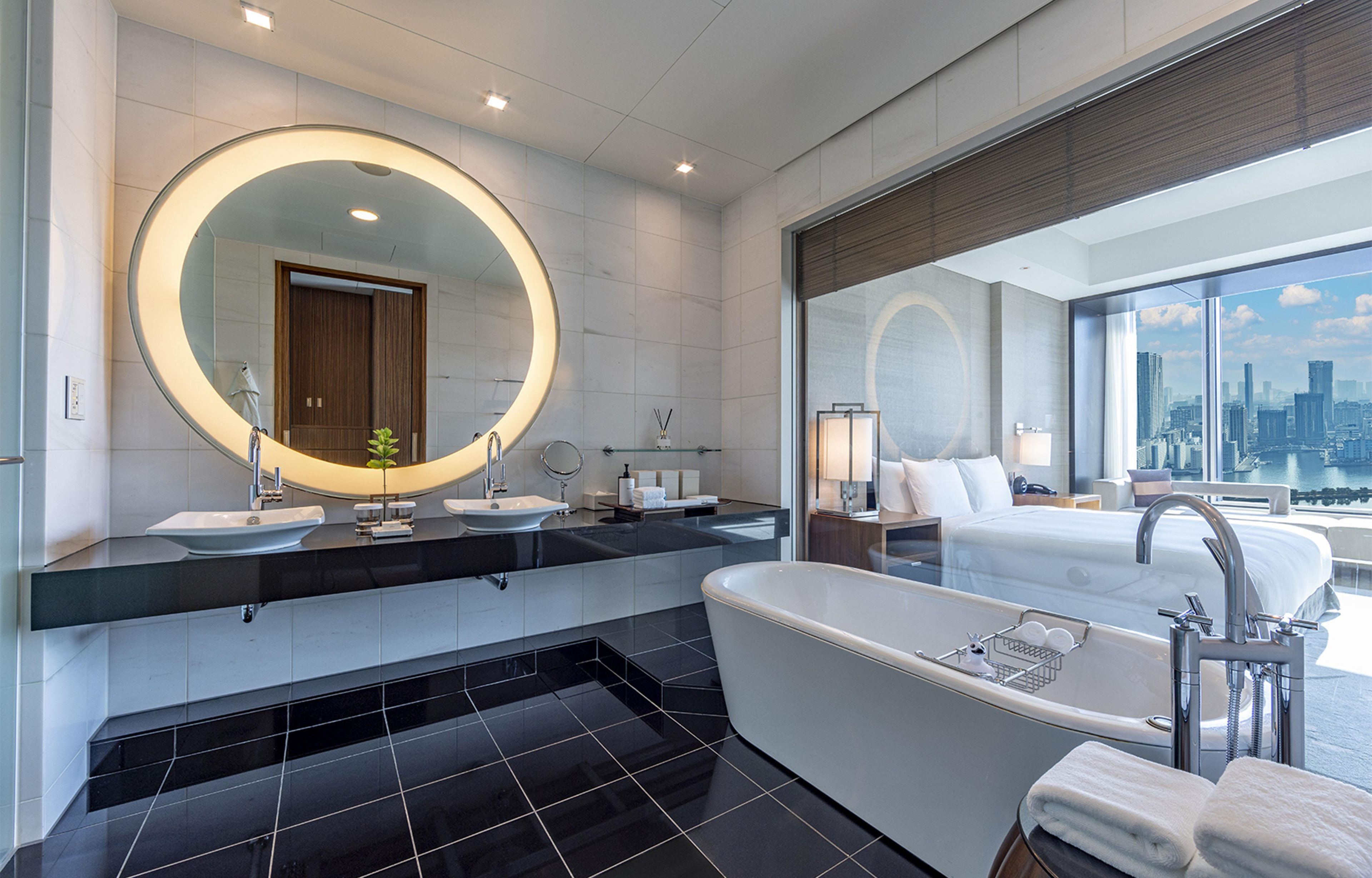 A modern bathroom with a large bathtub, two sinks, and a large mirror.