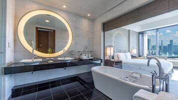 A modern bathroom with a large bathtub, two sinks, and a large mirror.