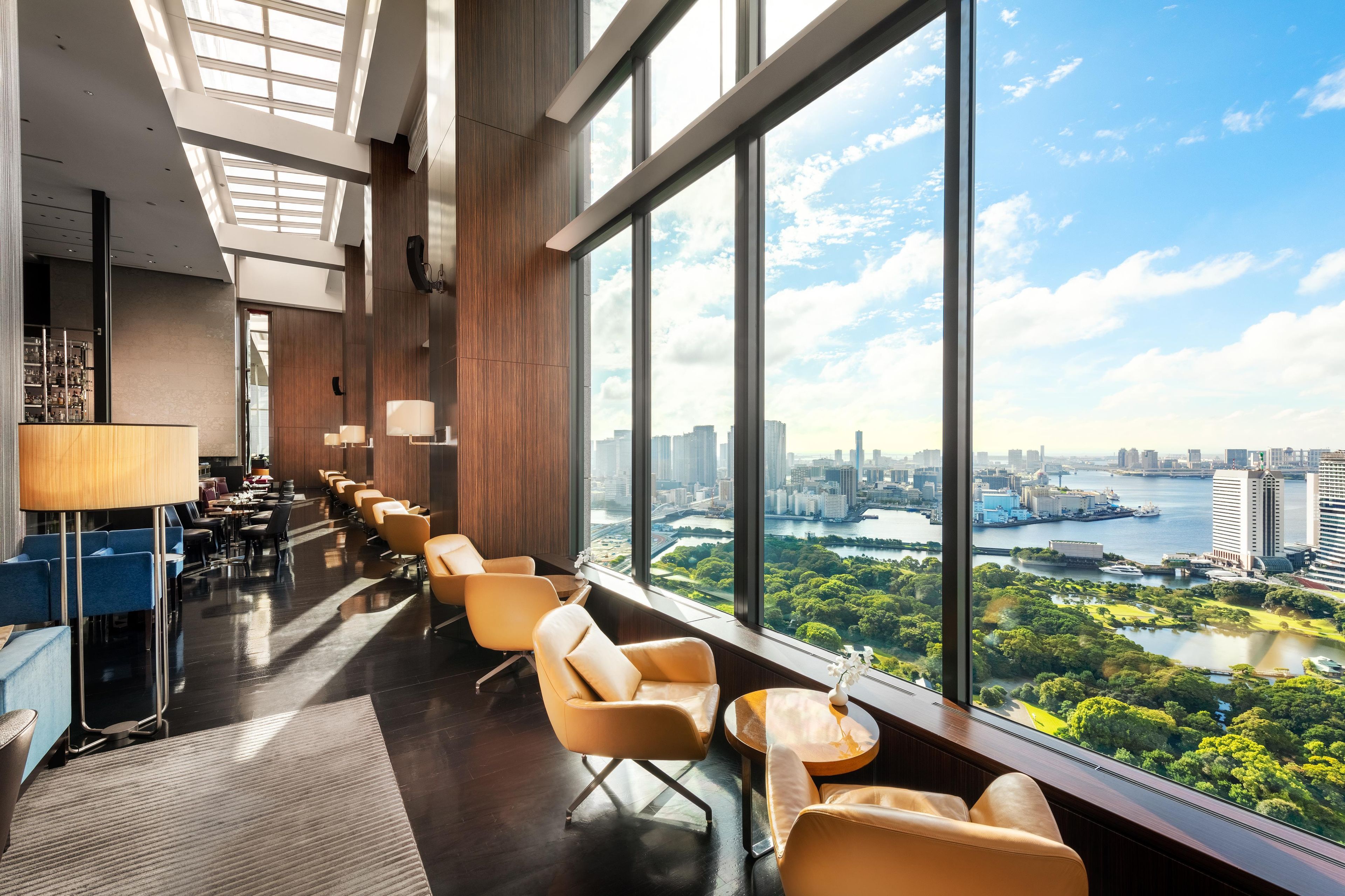 A modern hotel lobby with a city view, large windows, and seating areas.