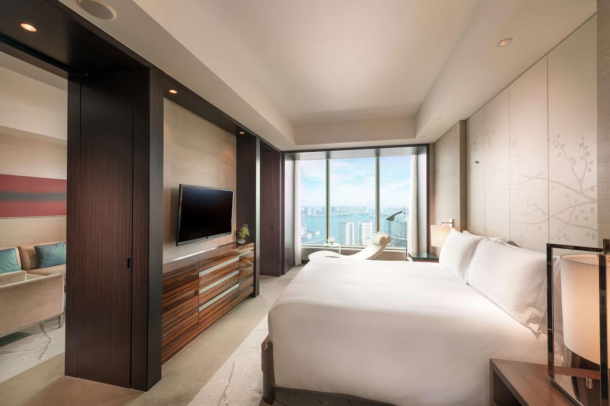 Una habitación de hotel moderna con una cama grande, televisión, vista a la ciudad y un balcón.