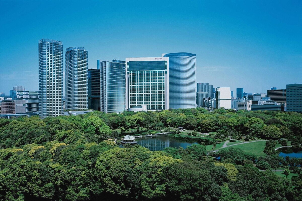 Un paisaje urbano con modernos rascacielos y un parque con un lago.