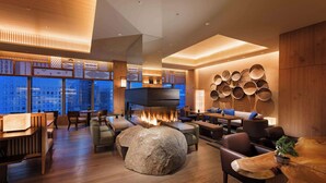 A modern lounge area with a large rock centerpiece, wooden furniture, and a wall of woven baskets. - Conrad Tokyo (Tokyo)