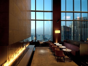 A modern interior with a fireplace, seating area, and large windows offering a city view.