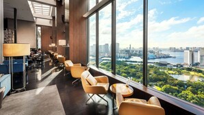 A modern hotel lobby with a view of a cityscape and a river. - Conrad Tokyo (Tokyo)