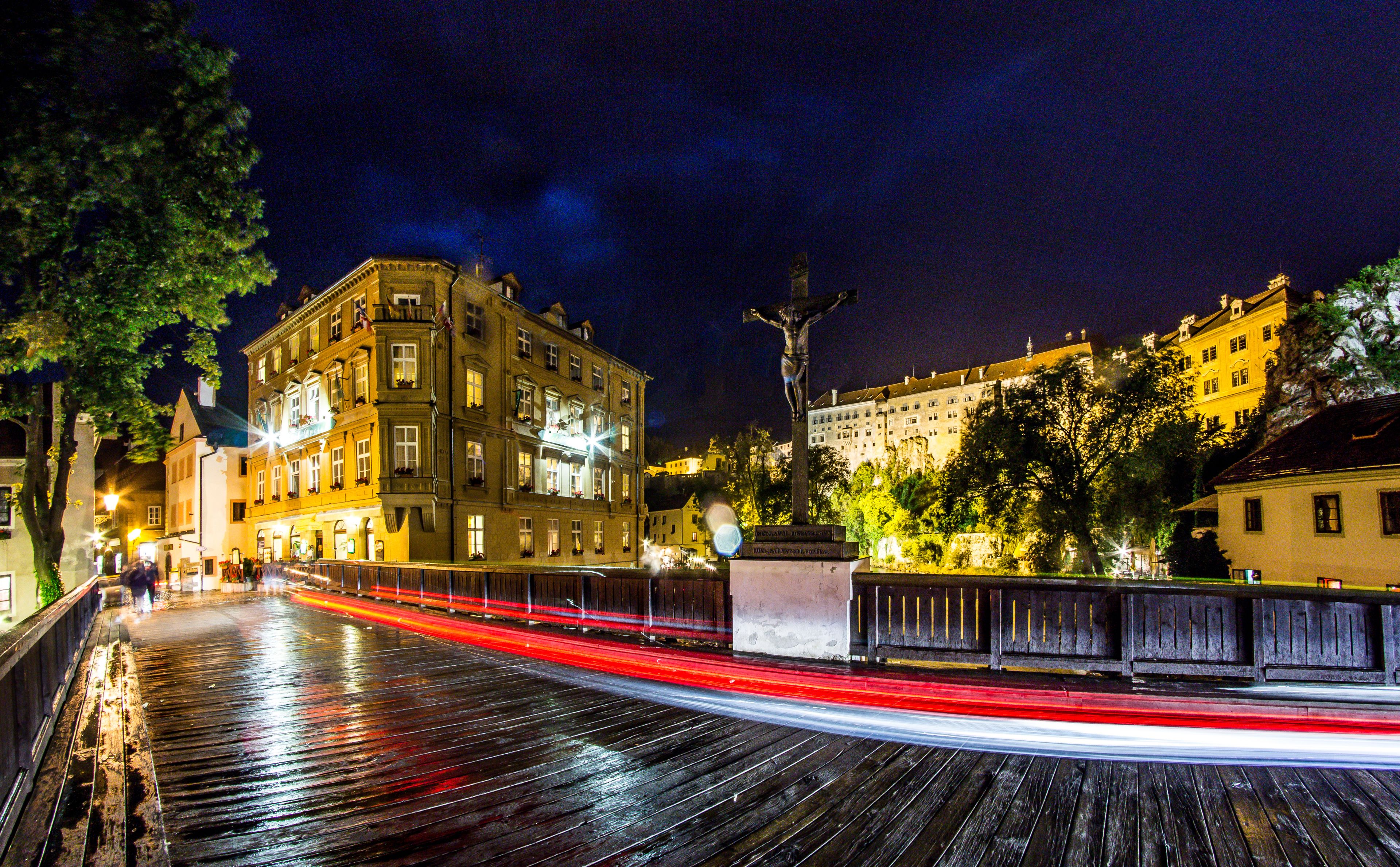A historic building with classical architecture, a prominent statue, and a wet wooden walkway.