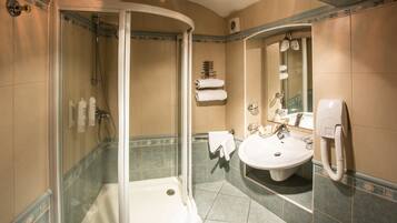 A bathroom with a glass-enclosed shower, a sink, and a mirror.