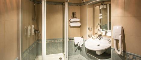 A bathroom with a glass-enclosed shower, a sink, and a mirror.