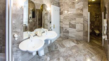 Une salle de bain avec deux lavabos, un miroir et un espace douche.