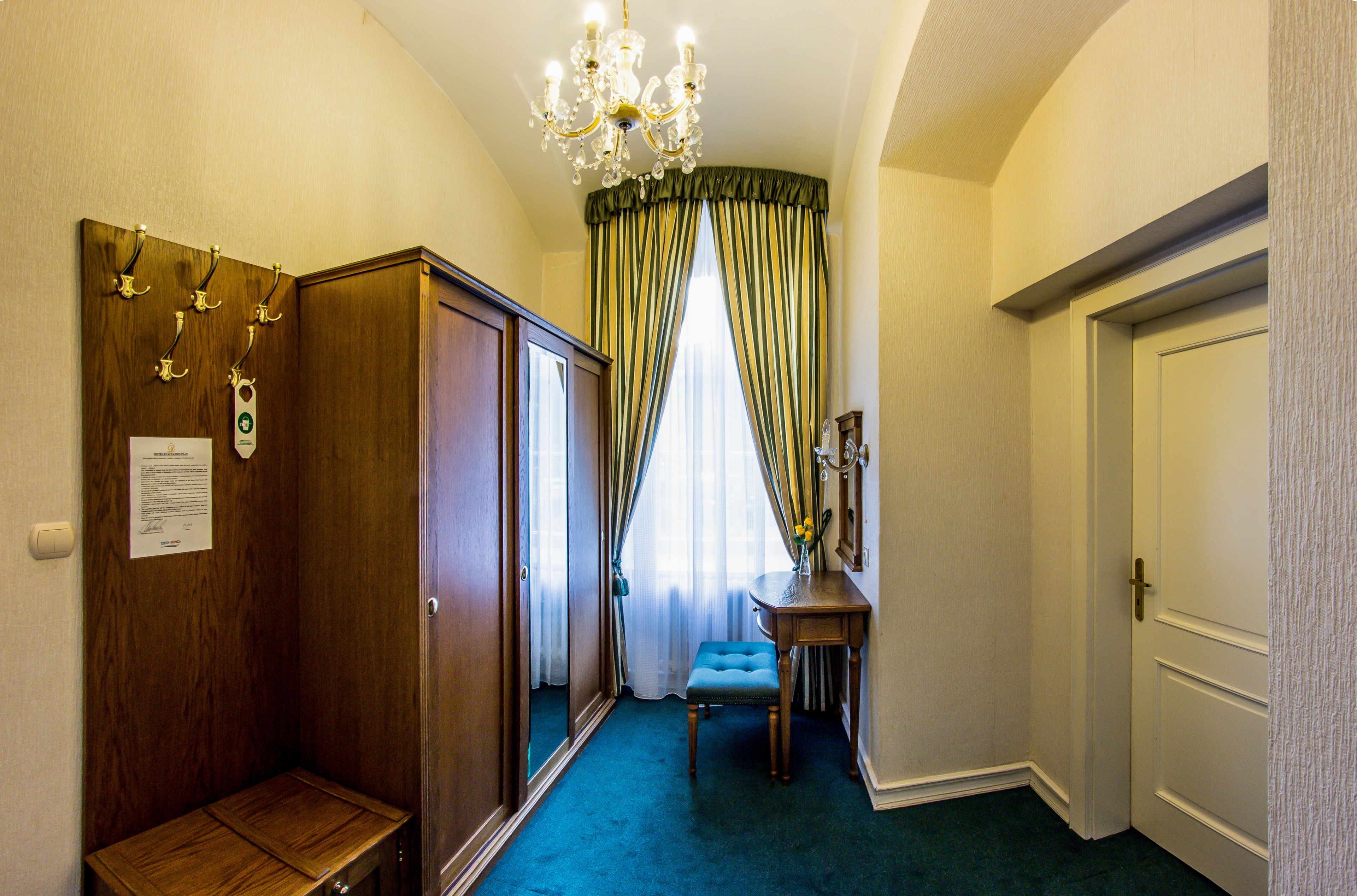 A hallway with a wooden wardrobe, a bench, a table with a vase, and a door.