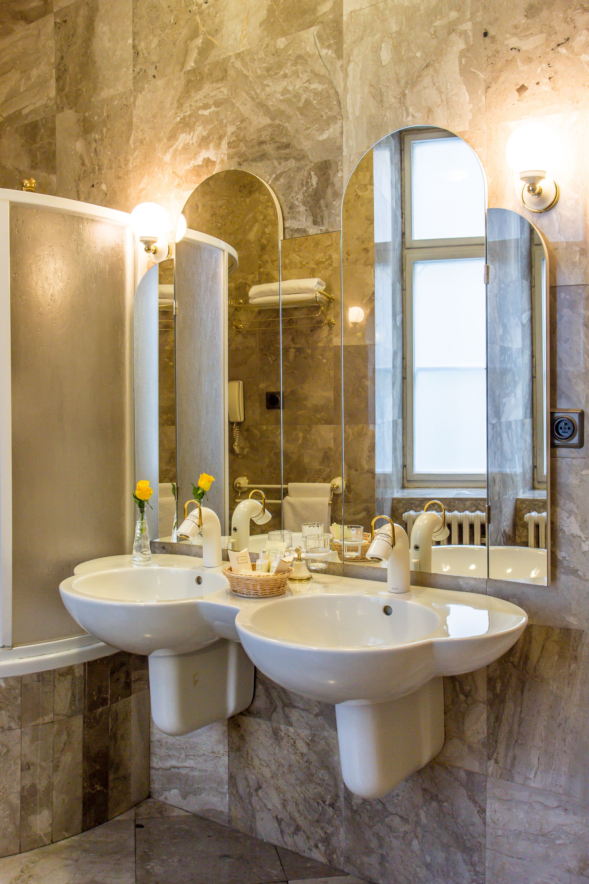 Un baño con dos lavamanos, un espejo grande y una ventana.