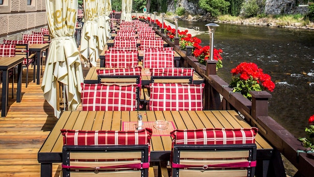 A riverside dining area with tables and chairs, umbrellas, and flowers. - Hotel Dvorak (Cesky Krumlov)