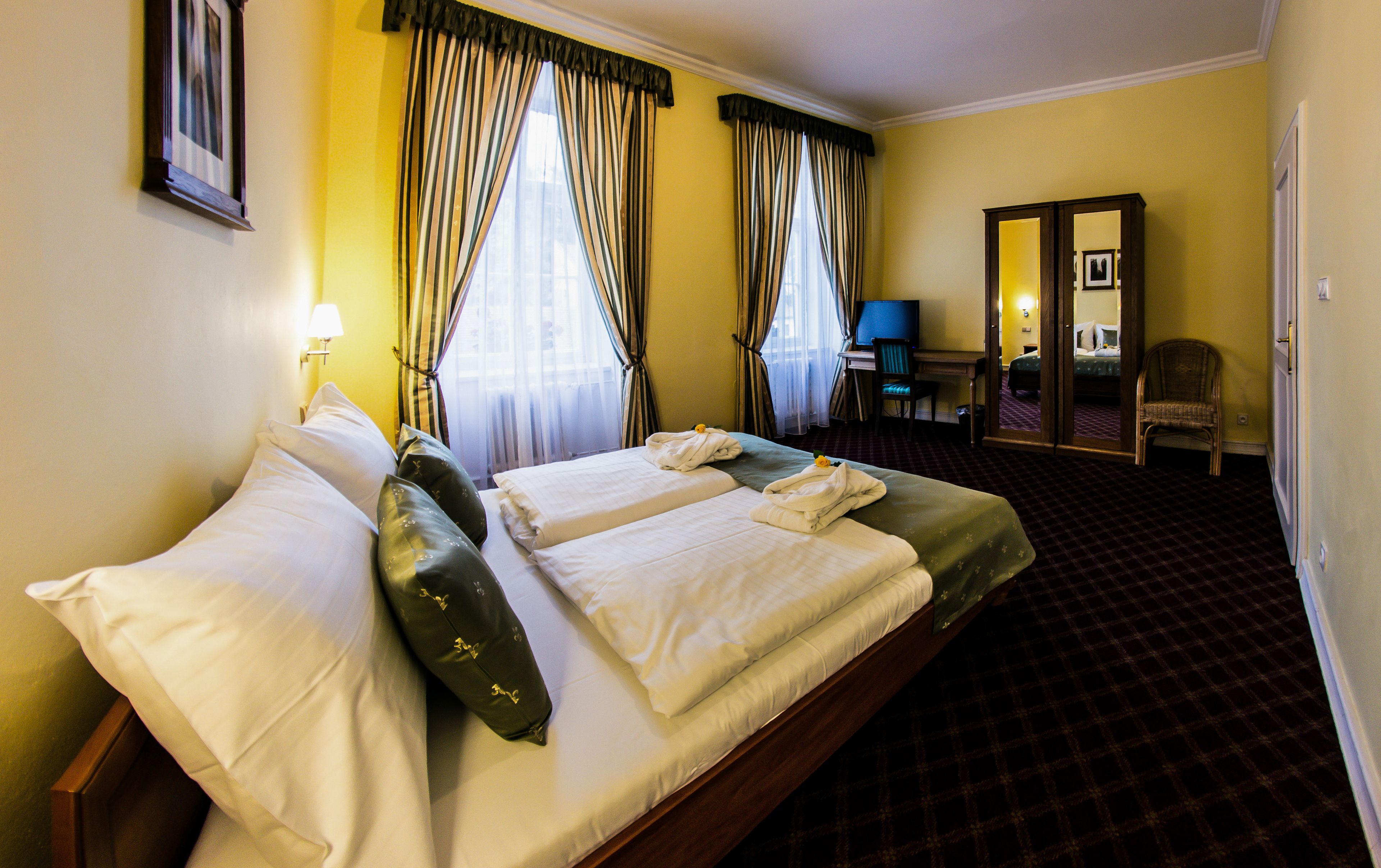 Ein Hotelzimmer mit zwei Betten, einem Schreibtisch, einem Stuhl und einem Spiegel.