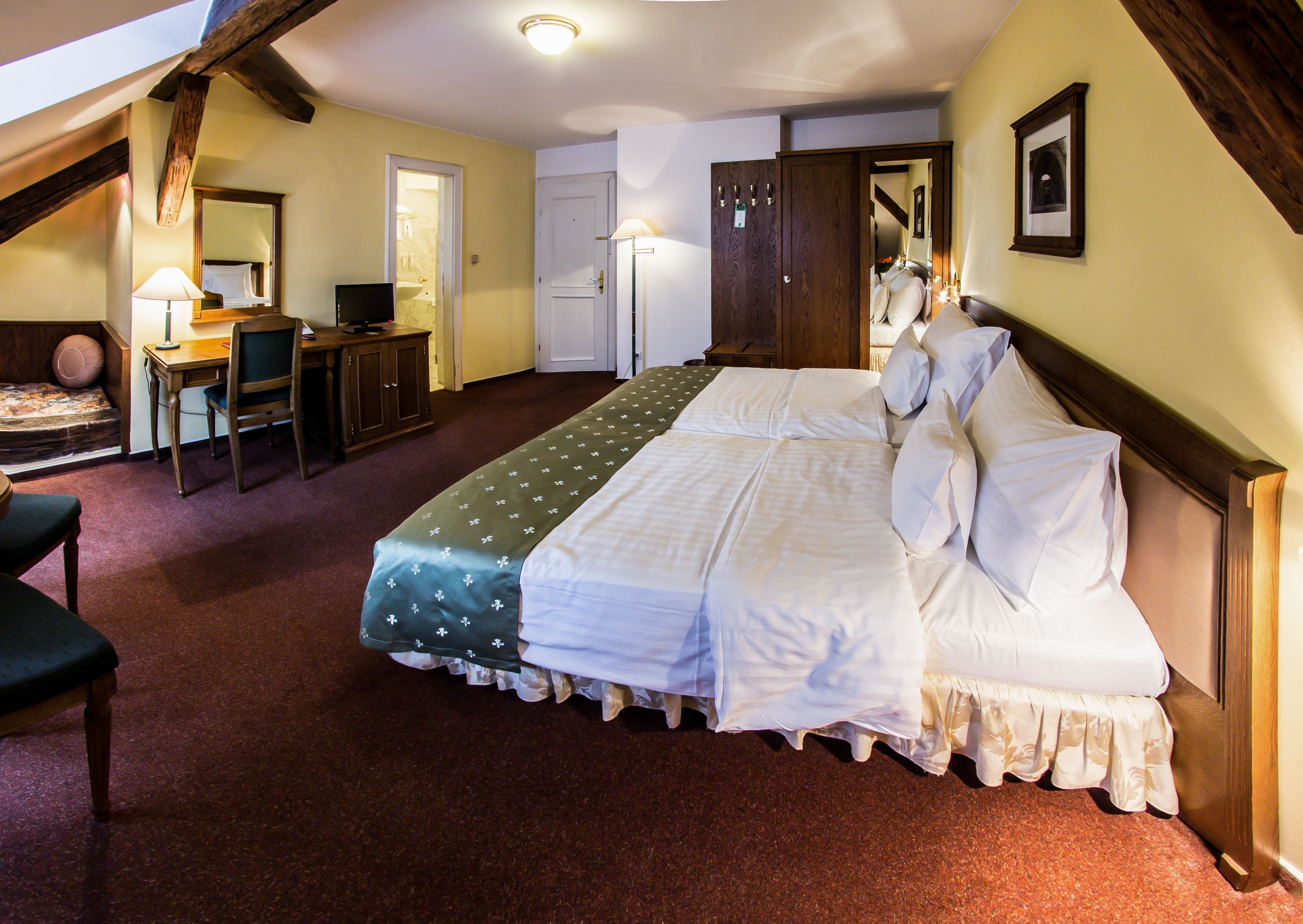 Ein Hotelzimmer mit Bett, Schreibtisch, Stuhl und Kleiderschrank.