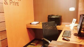 Ein Arbeitsplatz mit Schreibtisch, Stuhl, Computer und Drucker, sowie einem Schild mit der Aufschrift 'Connect & Print'.