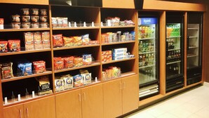 Un supermercado con estantes llenos de aperitivos y una sección de productos refrigerados.