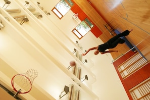 A gymnasium with a basketball hoop, exercise equipment, and a wooden floor.