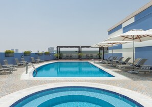 A rooftop pool with clear blue water, surrounded by lounge chairs and umbrellas. - Coral Dubai Deira Hotel (Dubai)