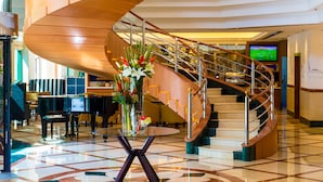 Un lobby imponente con una escalera de caracol, una araña y un piano.