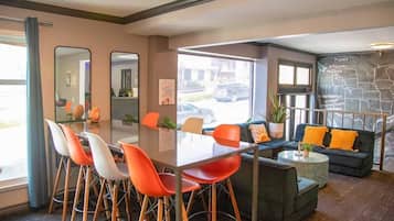 A modern interior with a dining area, seating, and a view of the street.
