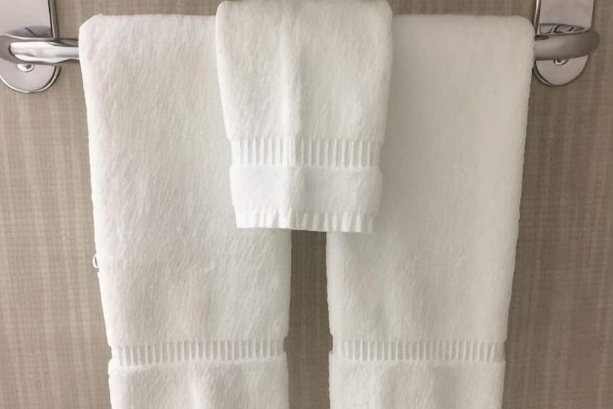 A bathroom with two white towels hanging on a towel rack.