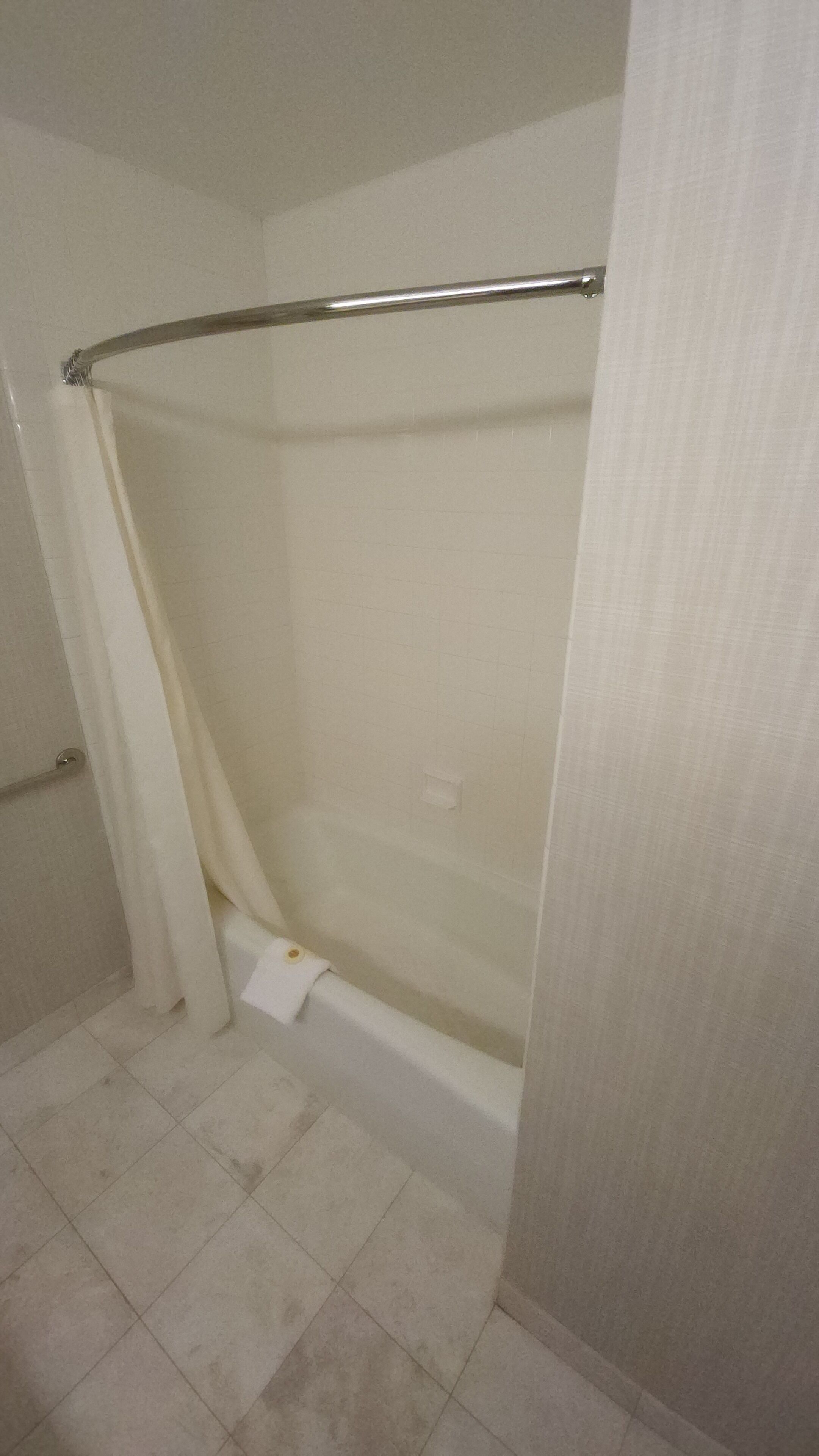 Une salle de bain avec un espace douche, un carrelage au sol et un porte-serviettes.