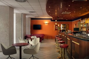 Zona de bar con mostrador, taburetes y pantalla de televisión.