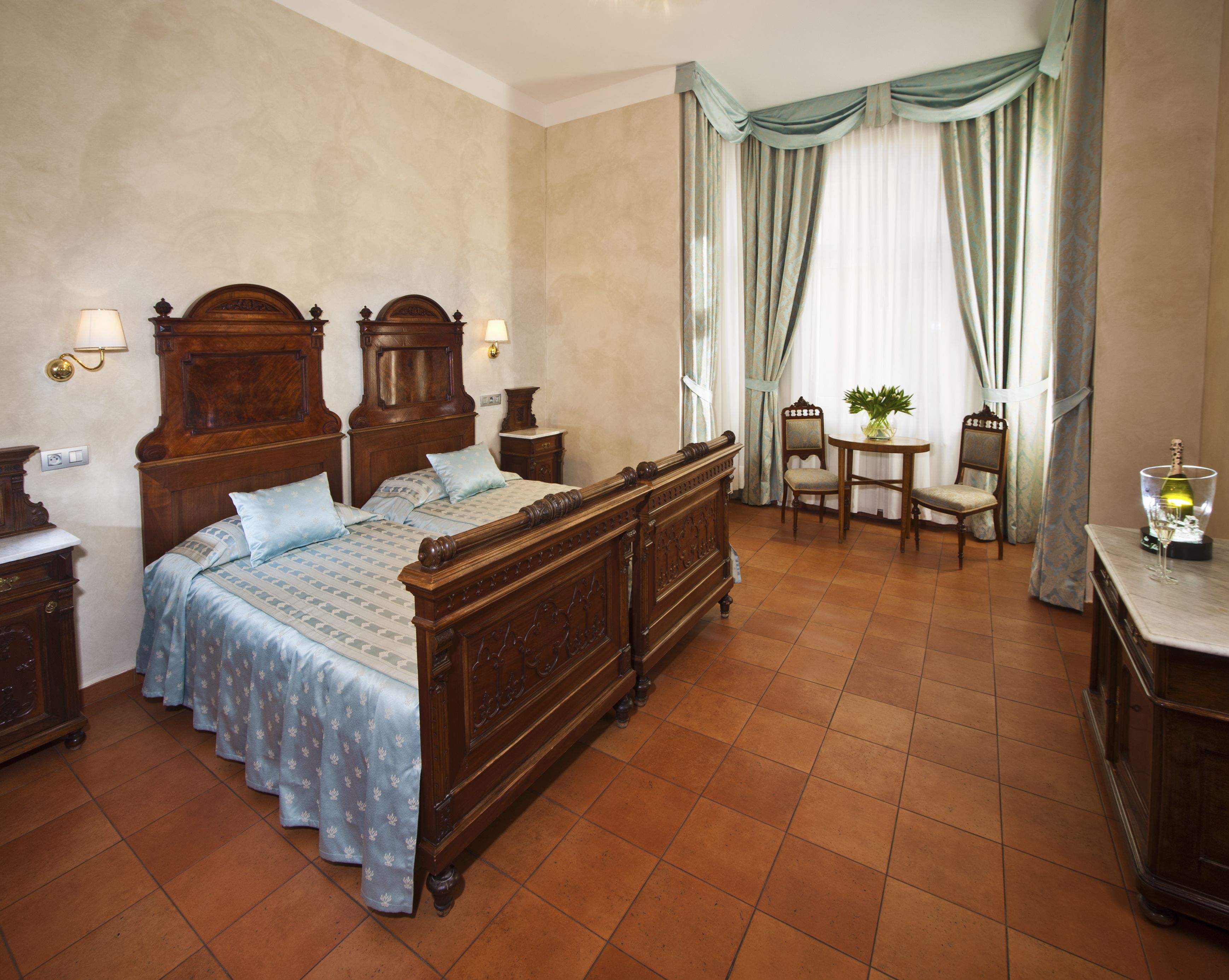 A traditional bedroom with a wooden bed, a small table with chairs, and a nightstand.