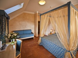Quarto com cama de dossel, sofá e área de jantar com mesa e cadeiras.
