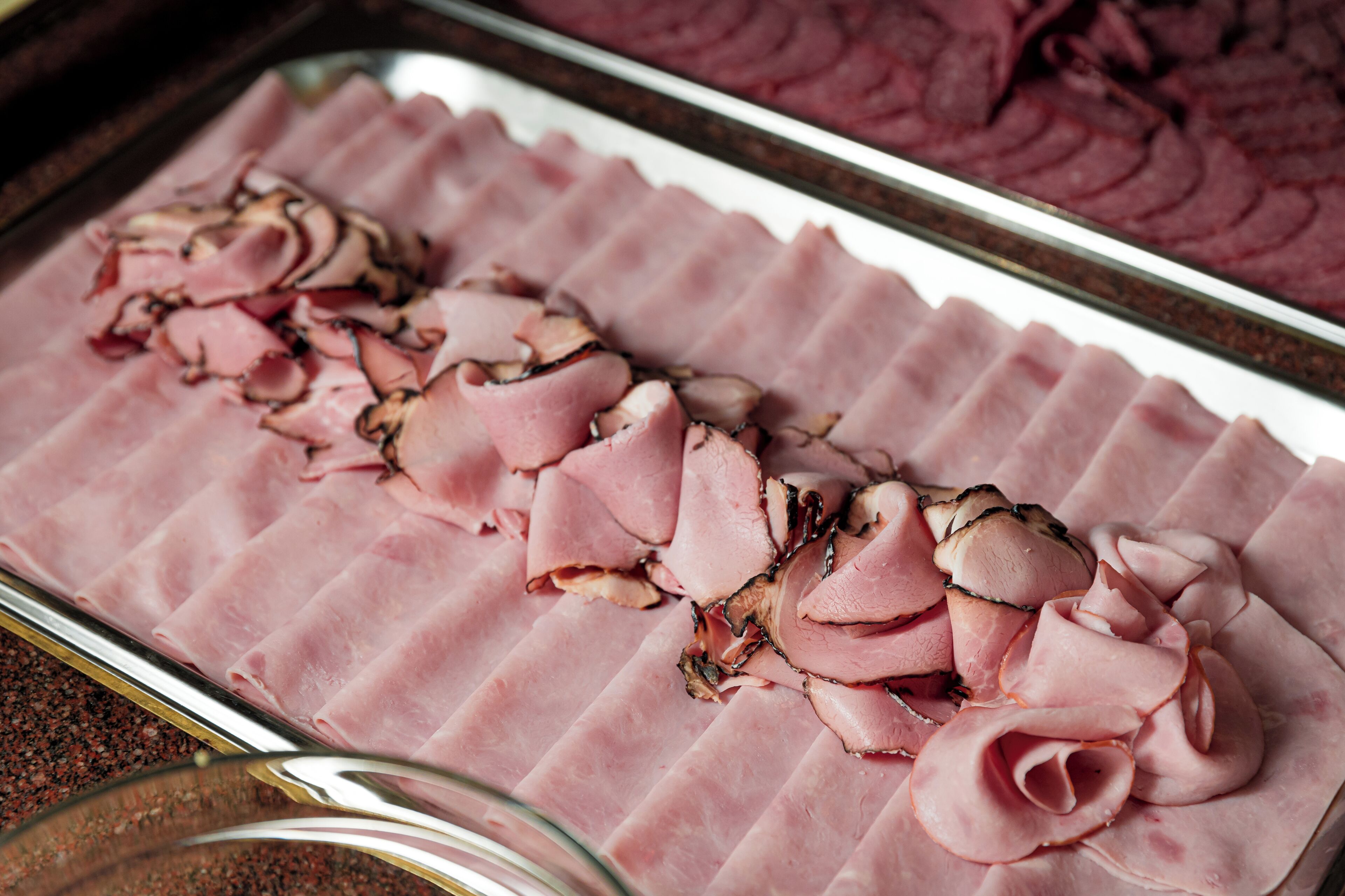 A tray of sliced ham arranged in a decorative pattern.