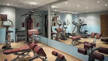 A gym with various exercise equipment, including treadmills, weight machines, and dumbbells.