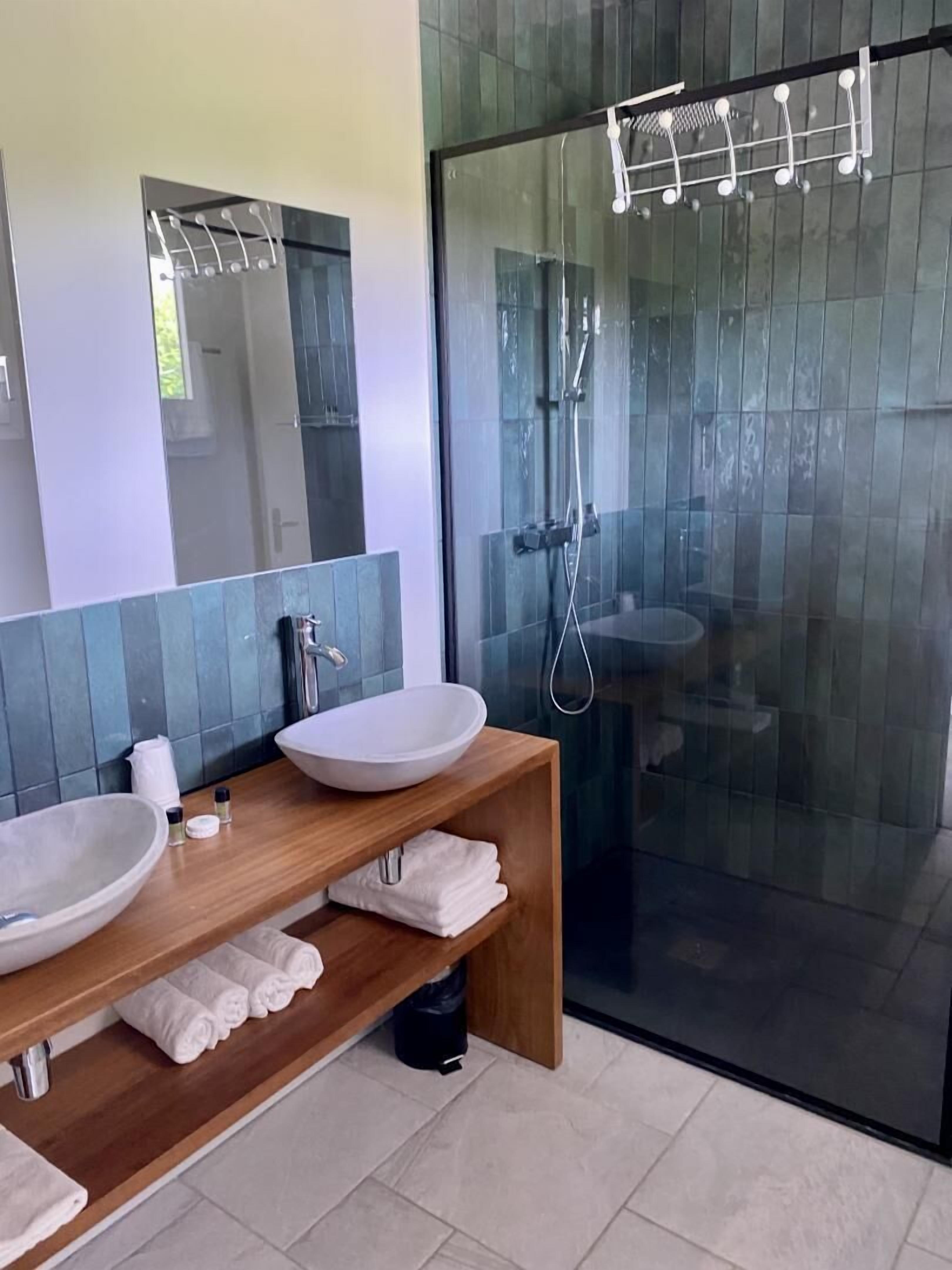 A modern bathroom with two large sinks, a wooden vanity, and a glass-enclosed shower area.
