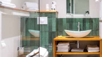 A modern bathroom with a glass shower enclosure, a white toilet, a wooden vanity with a sink, and a mirror above the mirror.