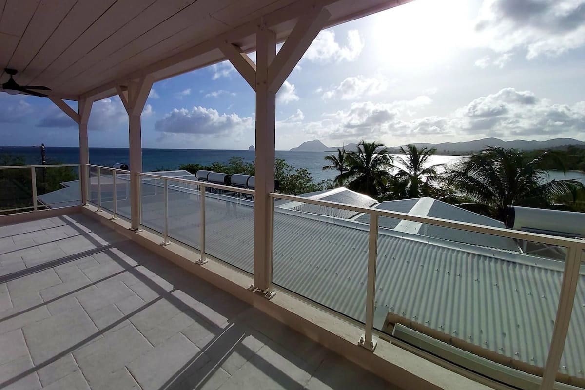 A covered balcony with a view of the sea and mountains.