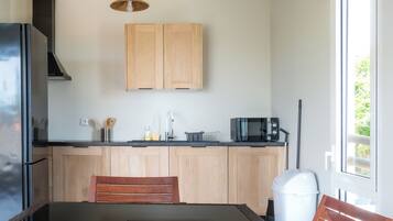 A modern kitchen with wooden cabinets, a black microwave, and a dining area with a wooden table and chairs.